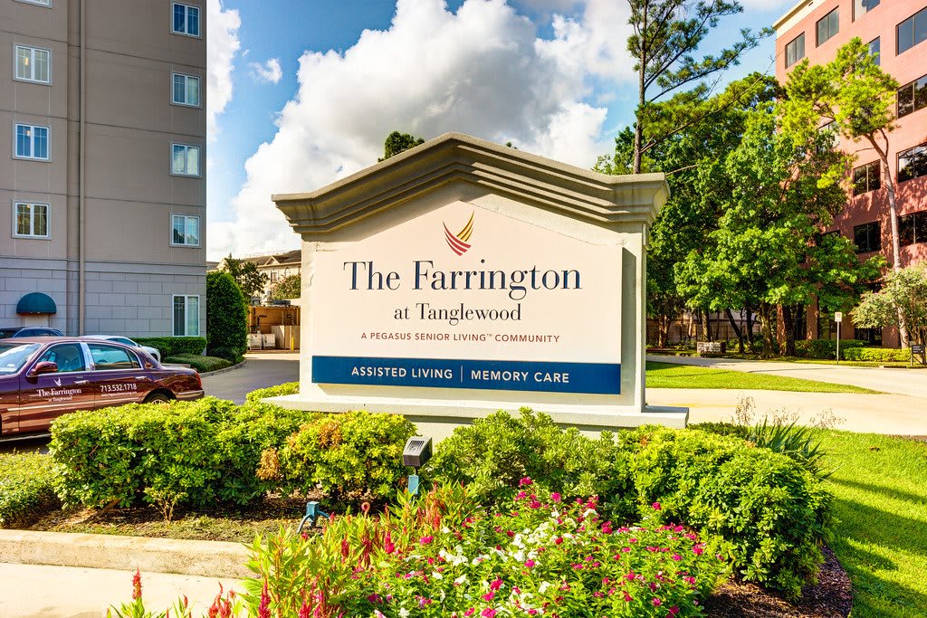 A sign for The Farrington at Tanglewood with a landscaped area and building in the background.
