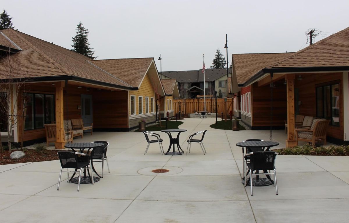 A courtyard with outdoor tables and chairs surrounded by buildings on an overcast day.
