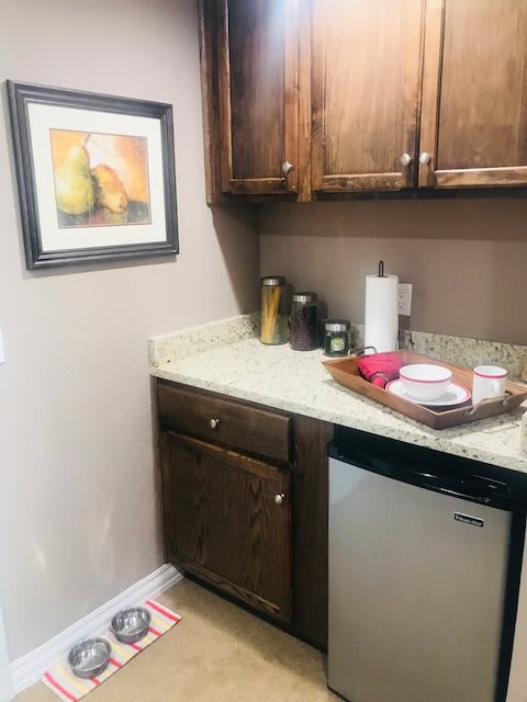 A small kitchen corner featuring a countertop with cups on a tray, paper towels, and decorative items.