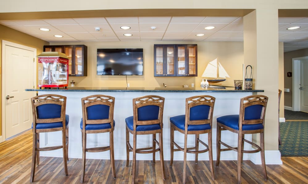 A stylish bar setting with wooden chairs and a large television.