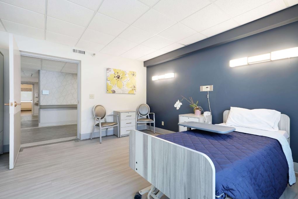 A modern hospital room with a patient bed and contemporary furnishings.