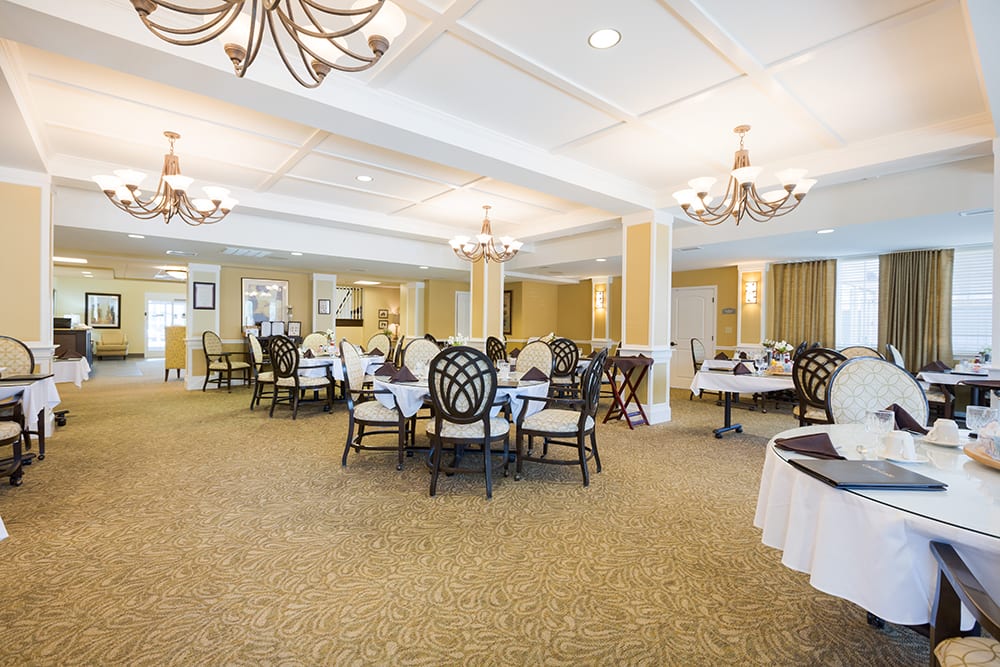 An elegant dining area with neatly arranged tables and chairs, adorned with chandeliers.