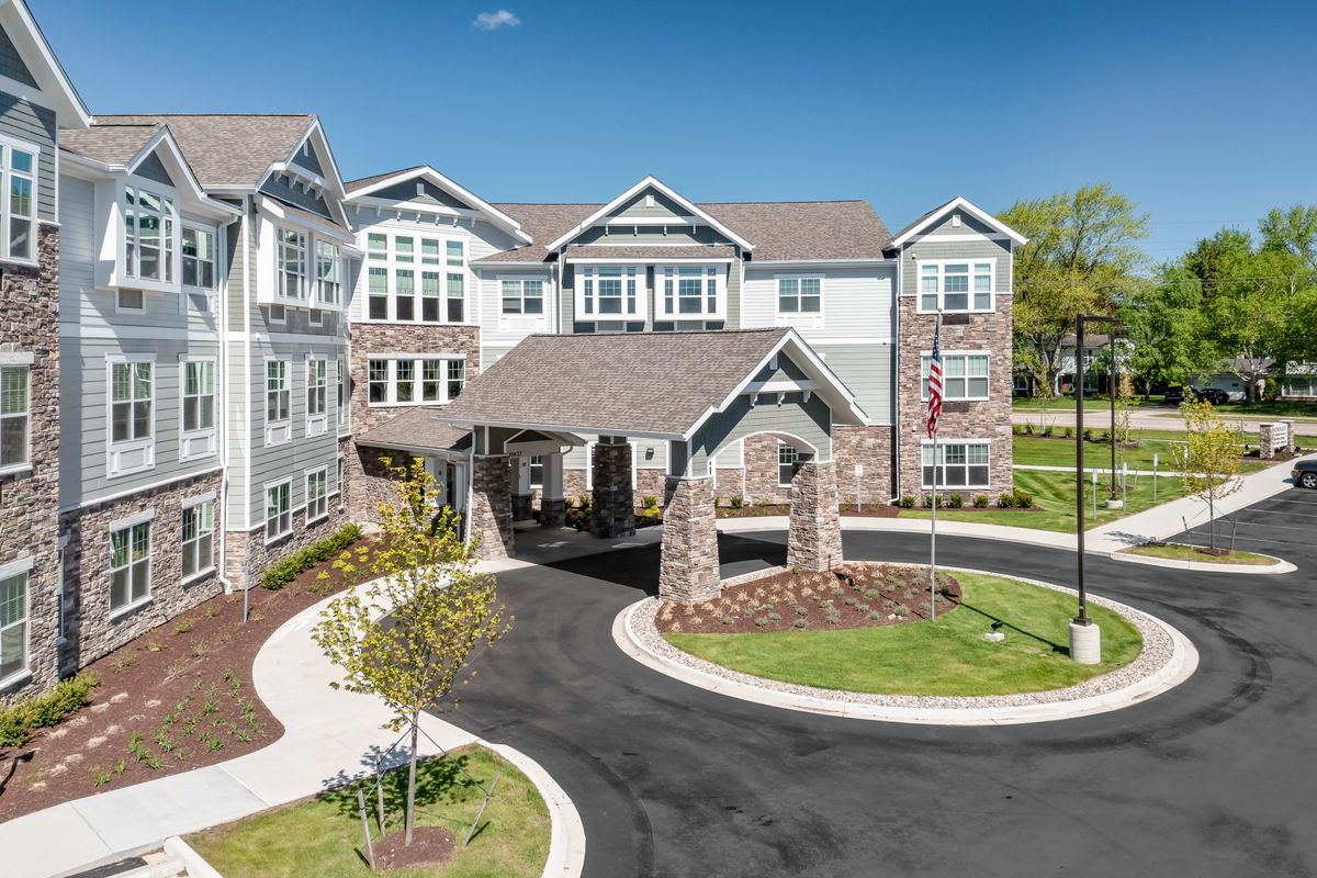 A modern residential building with landscaped surroundings and a circular driveway.