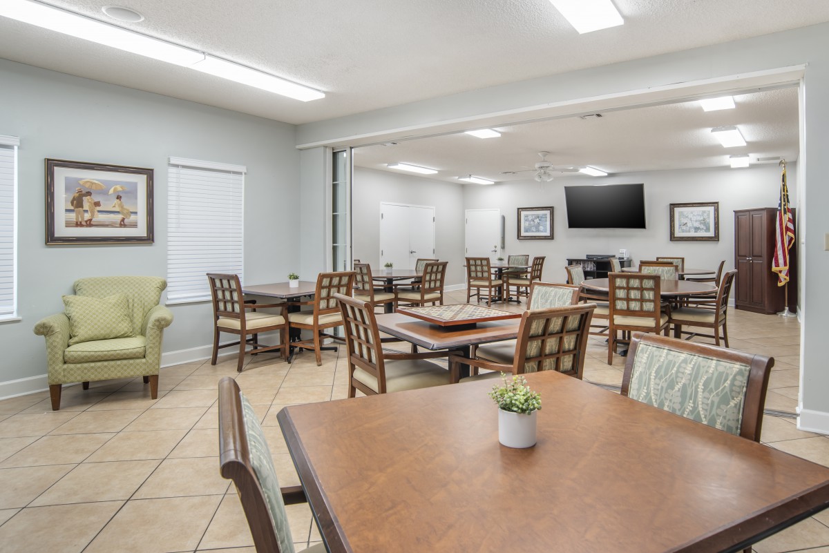 A modern dining room with multiple tables, chairs, and a wall-mounted television.