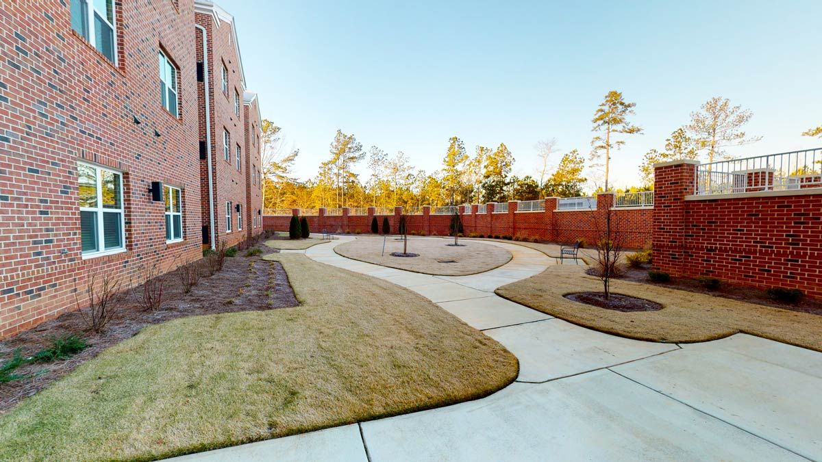A landscaped courtyard with pathways and surrounding trees beside a building.