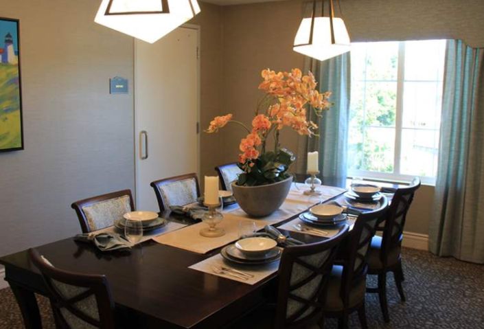 A well-set dining room table with elegant decor and a central orchid arrangement.