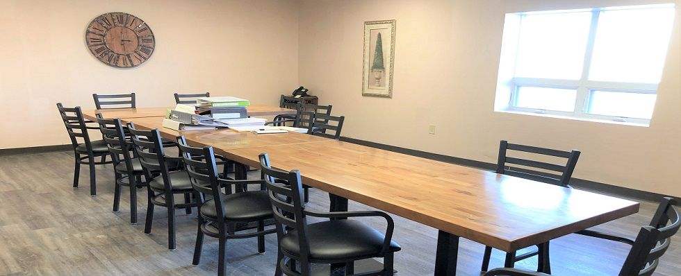 A conference room with a long wooden table and several chairs, ready for a meeting.