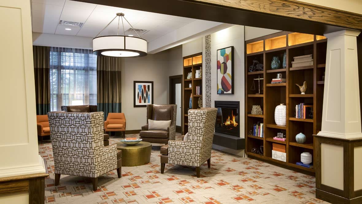 A modern lounge area with comfortable seating, a fireplace, and decorative art.