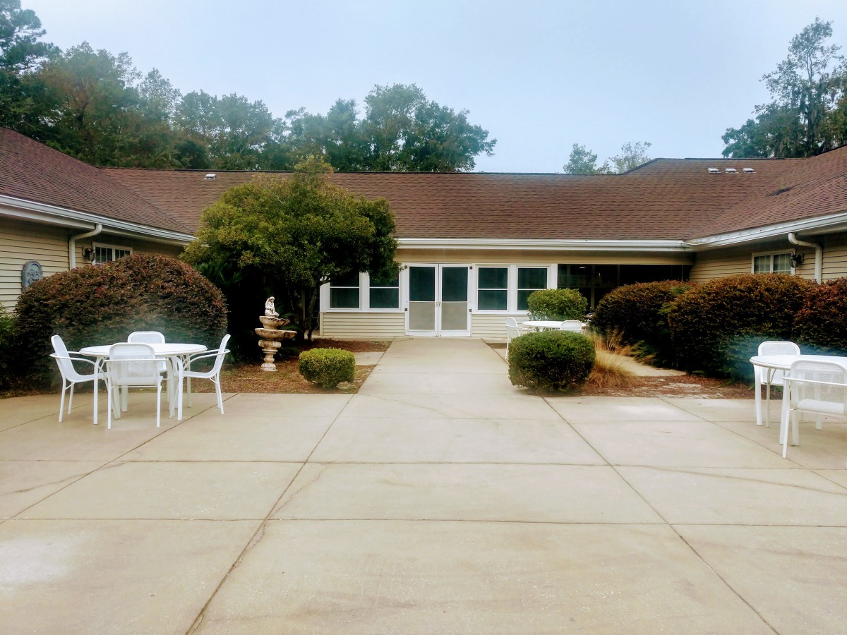 A suburban house with a courtyard featuring outdoor seating and landscaped bushes.