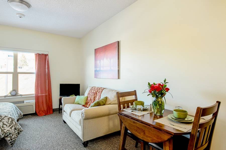 A cozy living room featuring a sofa, dining table with flowers, and warm decor.