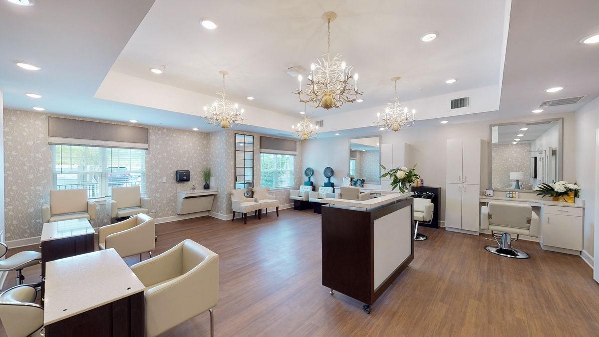 A modern and elegant reception area featuring stylish chandeliers, comfortable seating, and wood flooring.