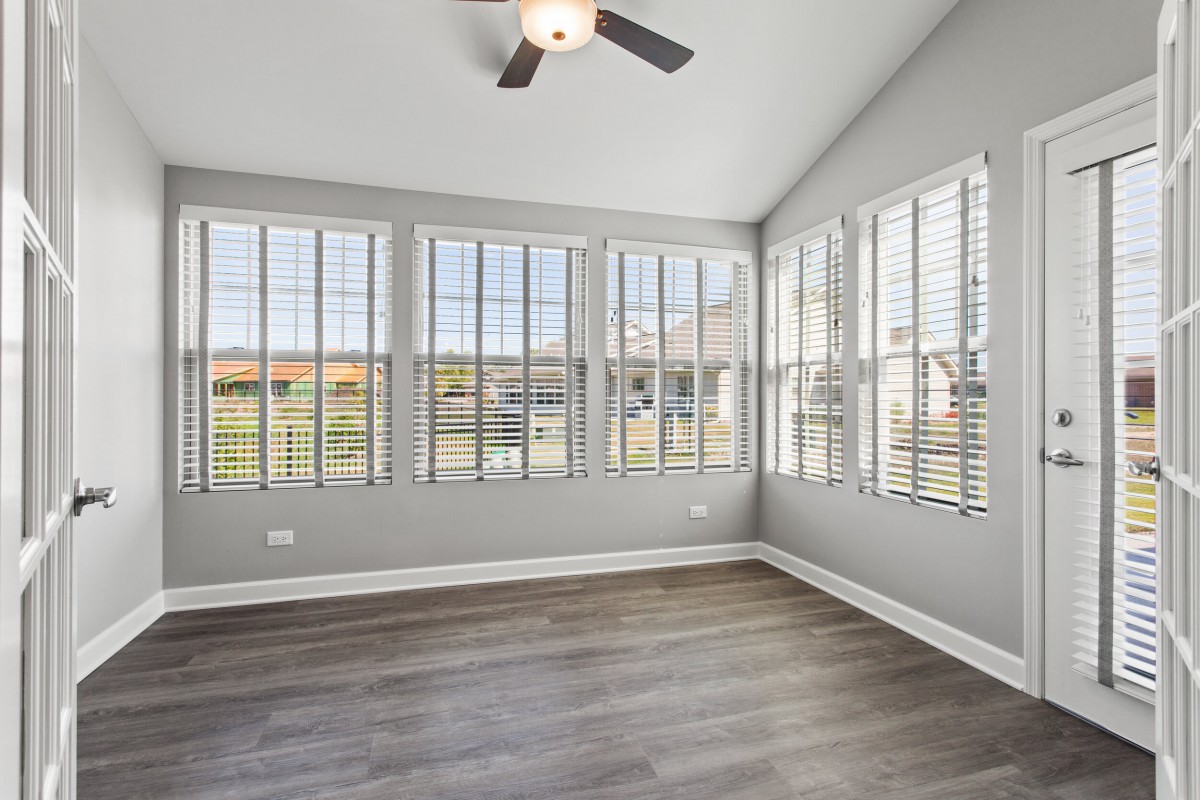 A bright and modern sunroom with large windows and wood flooring.