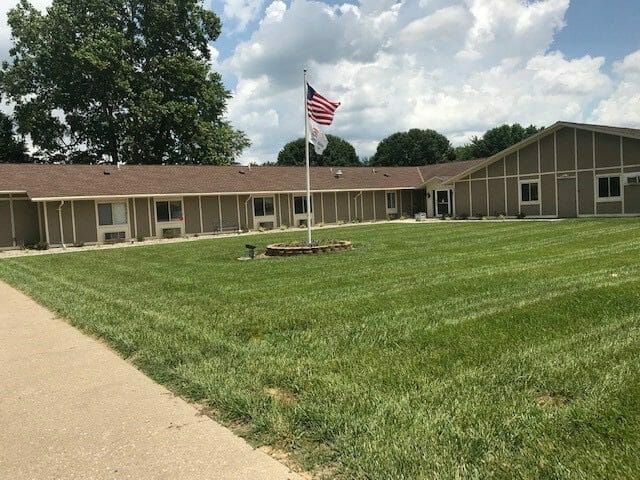 A large building with a well-maintained lawn and an American flag flying in the yard.