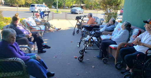 Elderly residents enjoy a sunny day outside a care facility.