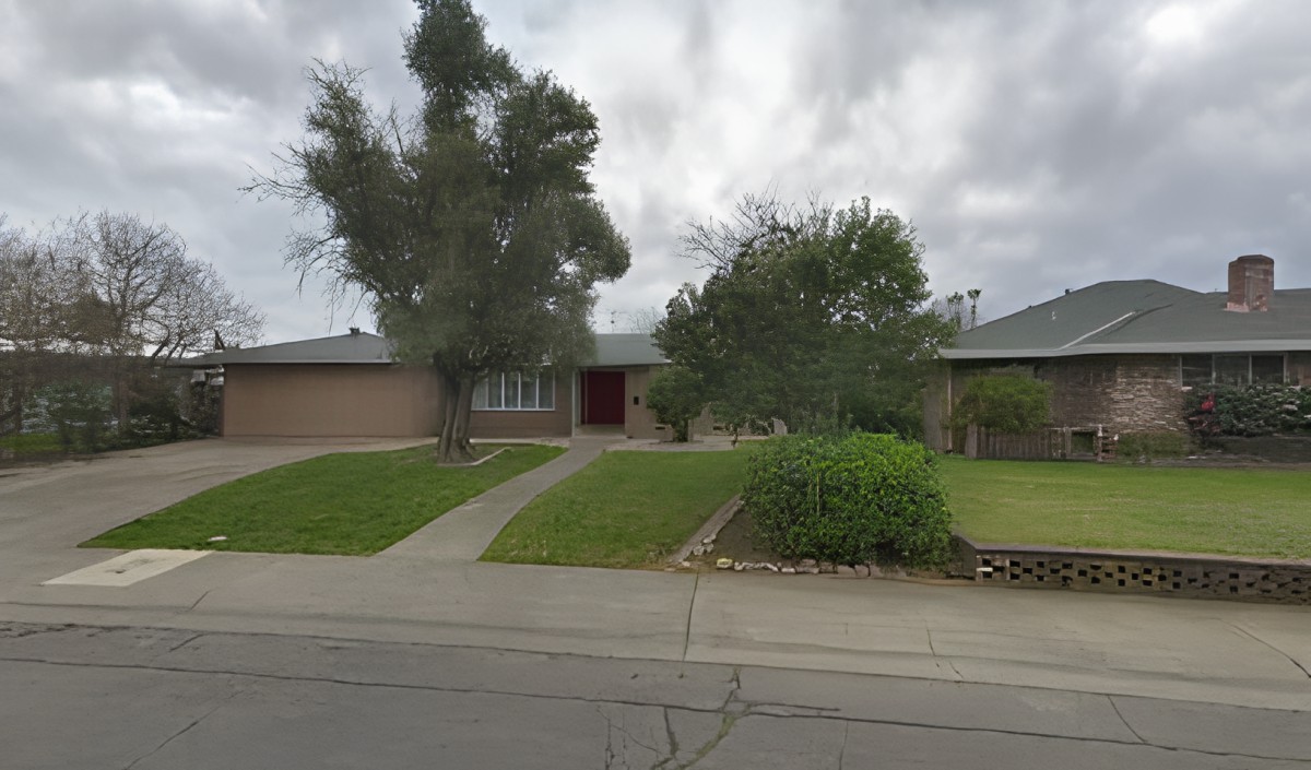 A suburban residential house with a lawn and trees.
