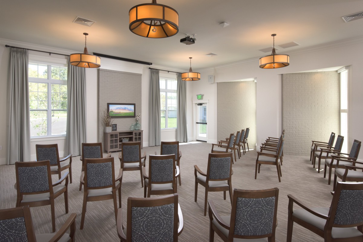 A well-lit conference room with arranged seating and a television.