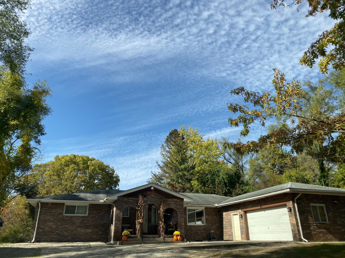 A suburban house with a clear blue sky and surrounding trees.