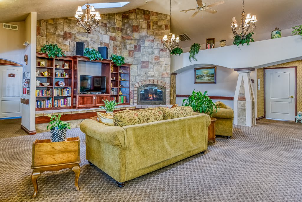 A cozy living room with a stone fireplace, comfortable sofas, and greenery.