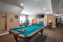 A cozy game room featuring a pool table, fireplace, and television.
