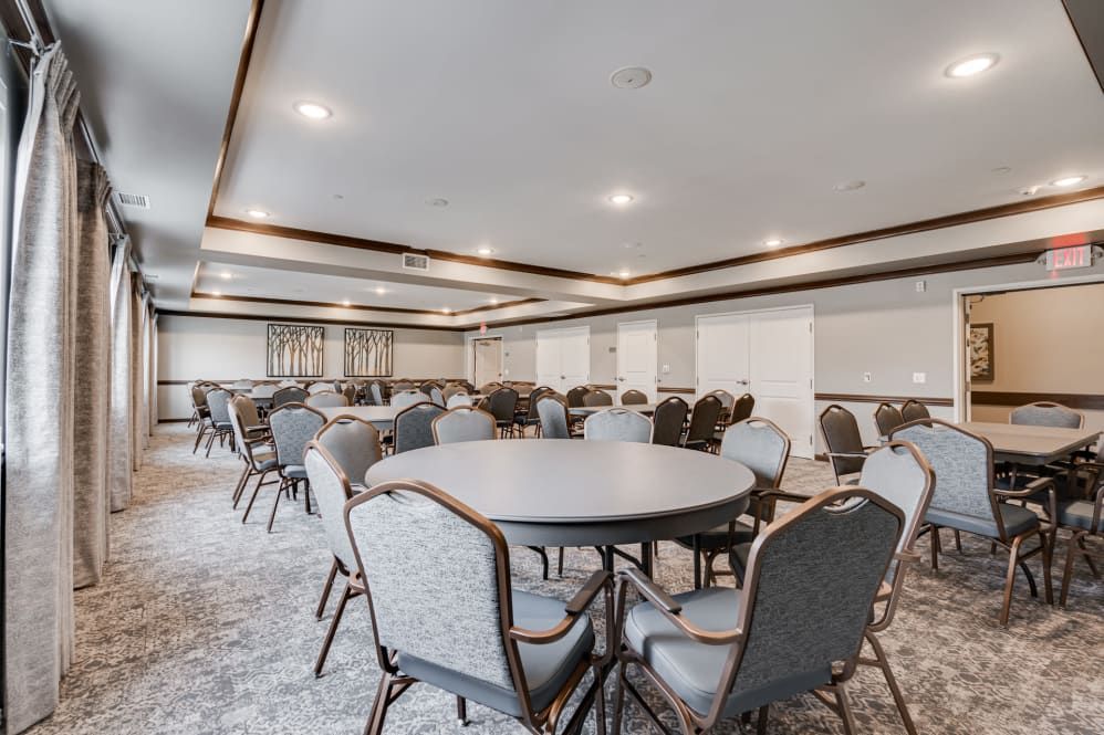 A spacious conference room with round tables and comfortable chairs, ready for a meeting or event.