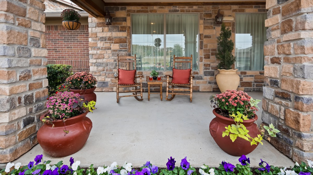 A cozy porch with rocking chairs and colorful flower pots.