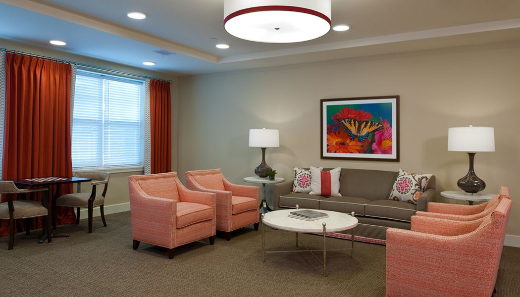 A stylish living room with coral armchairs, a gray sofa, and vibrant artwork on the wall.