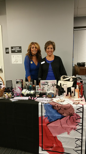 Two women showcasing a variety of beauty and cosmetic products at an event.