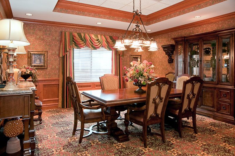 A traditionally decorated dining room with a wooden table, upholstered chairs, and an elegant chandelier.