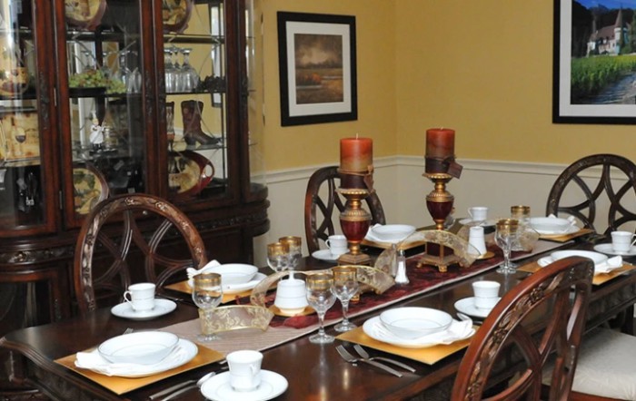 A formal dining room with an elegantly set table, complete with plates, cups, and decorative candles.