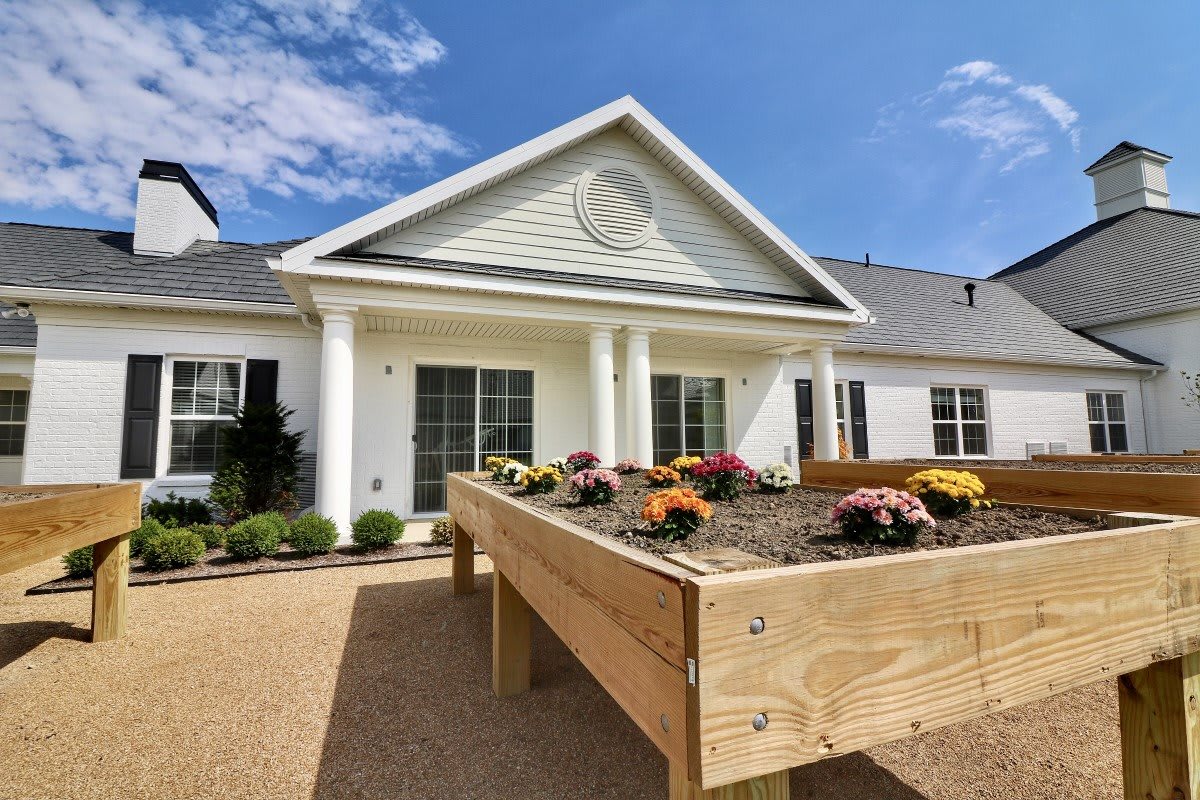 A beautiful residential house with a raised garden bed filled with colorful flowers on a sunny day.