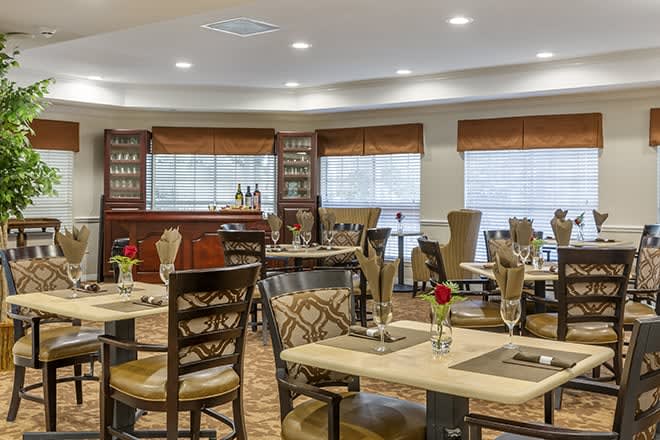 A cozy restaurant interior with neatly arranged tables and a bar in the background.