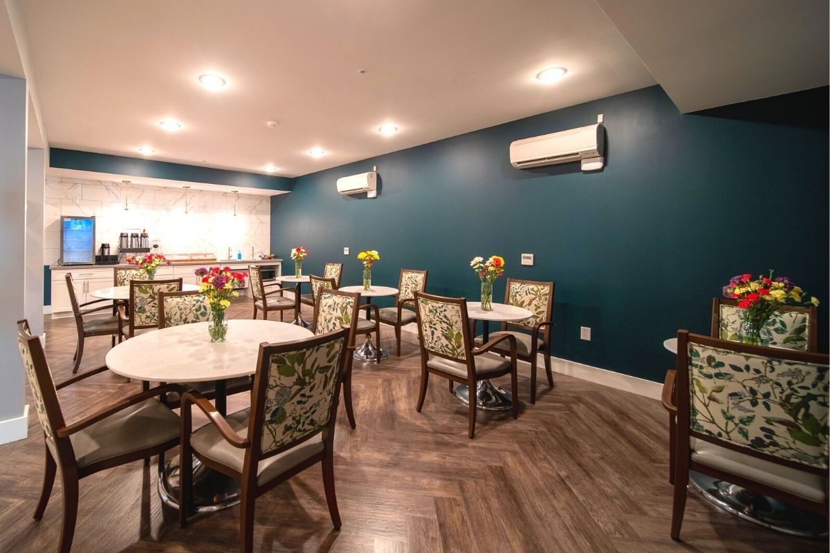 A cozy dining area with elegant decor, featuring tables adorned with floral arrangements and a modern design aesthetic.