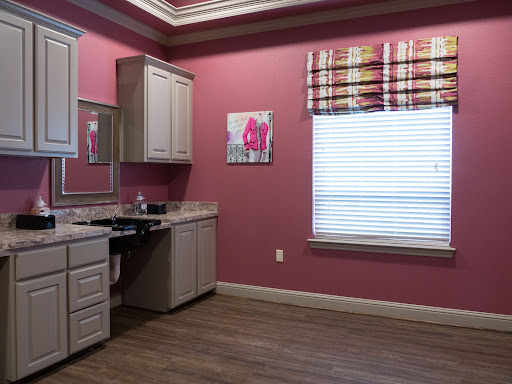 A cozy kitchen space featuring pink walls and modern cabinetry, illuminated by natural light from a window.