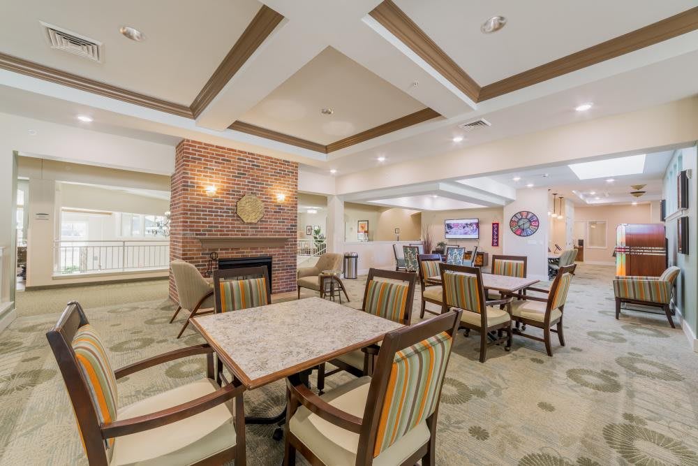 A well-lit dining area with tables and chairs, featuring a fireplace and decorative ceiling design.