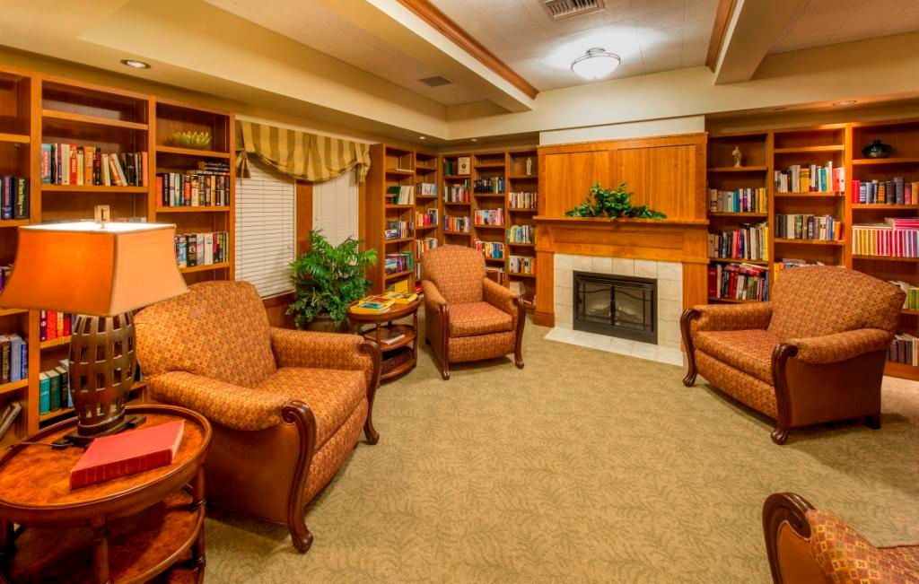 A cozy reading room with comfortable armchairs, a fireplace, and well-stocked bookshelves.