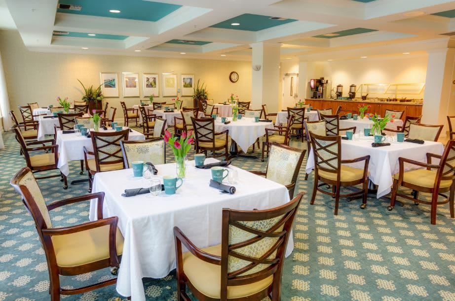 An elegant restaurant interior featuring neatly arranged tables with white tablecloths and comfortable chairs.