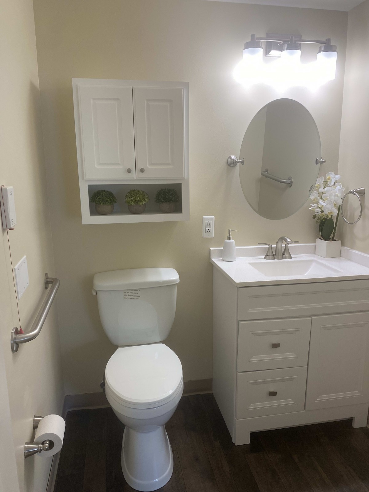 A modern and clean bathroom with a toilet, sink, mirror, and cabinet.