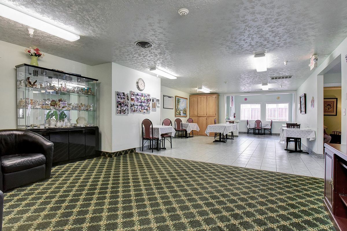 A spacious hotel lobby with carpet flooring and tables set with white tablecloths.