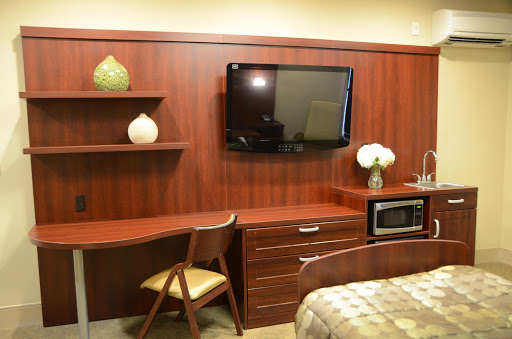 A cozy interior featuring a wooden desk, a wall-mounted television, and a microwave in a neatly arranged living space.