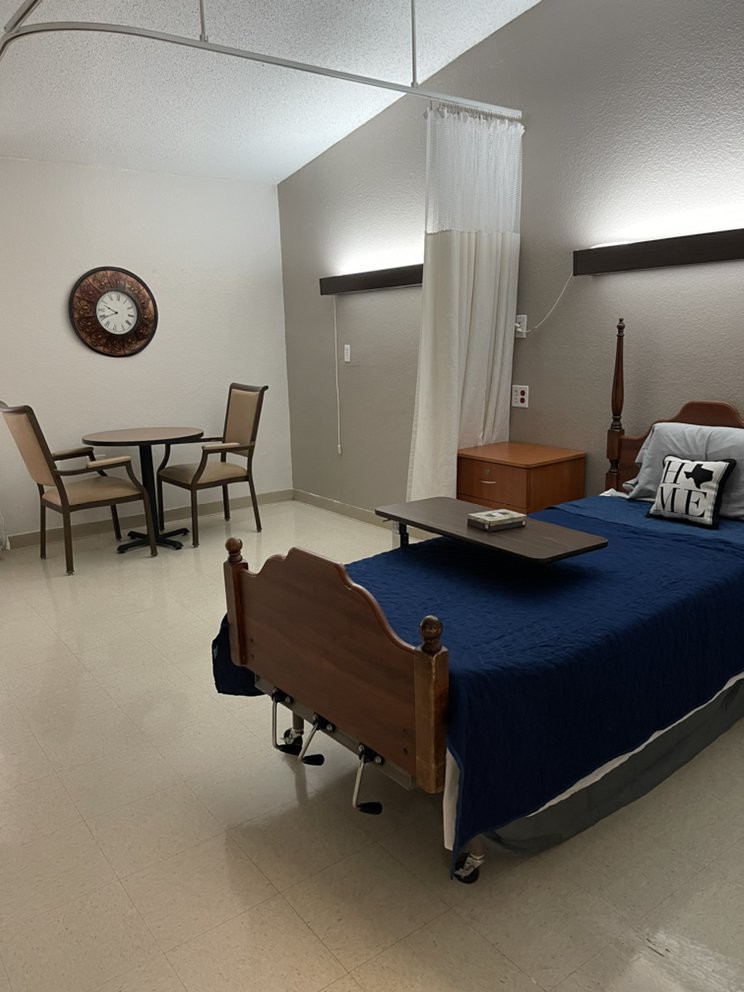 A well-organized hospital room with a bed, table, and chairs.