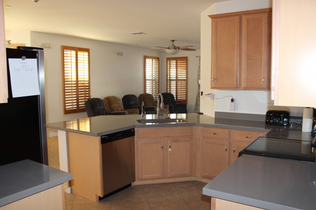 An open kitchen with wooden cabinets and a view into a living area.