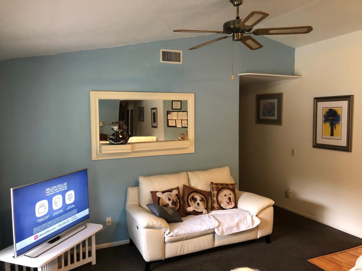 A cozy living room with a comfortable sofa, a large mirror on the wall, and a television in the corner.
