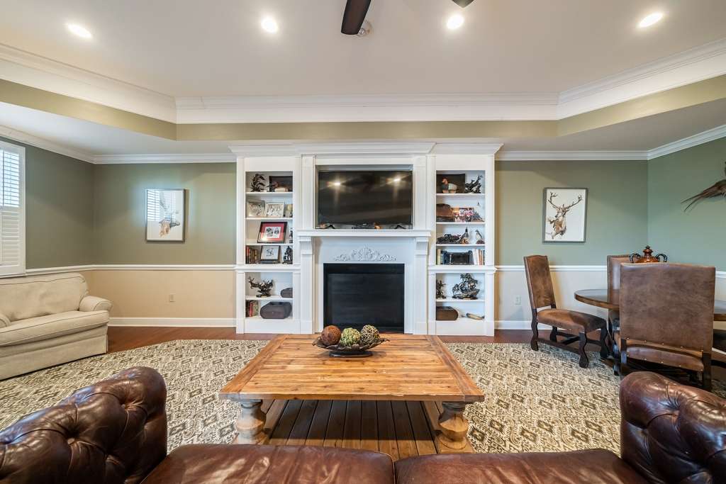 A cozy living room featuring a central fireplace with a mounted television, surrounded by built-in shelves and comfortable seating.