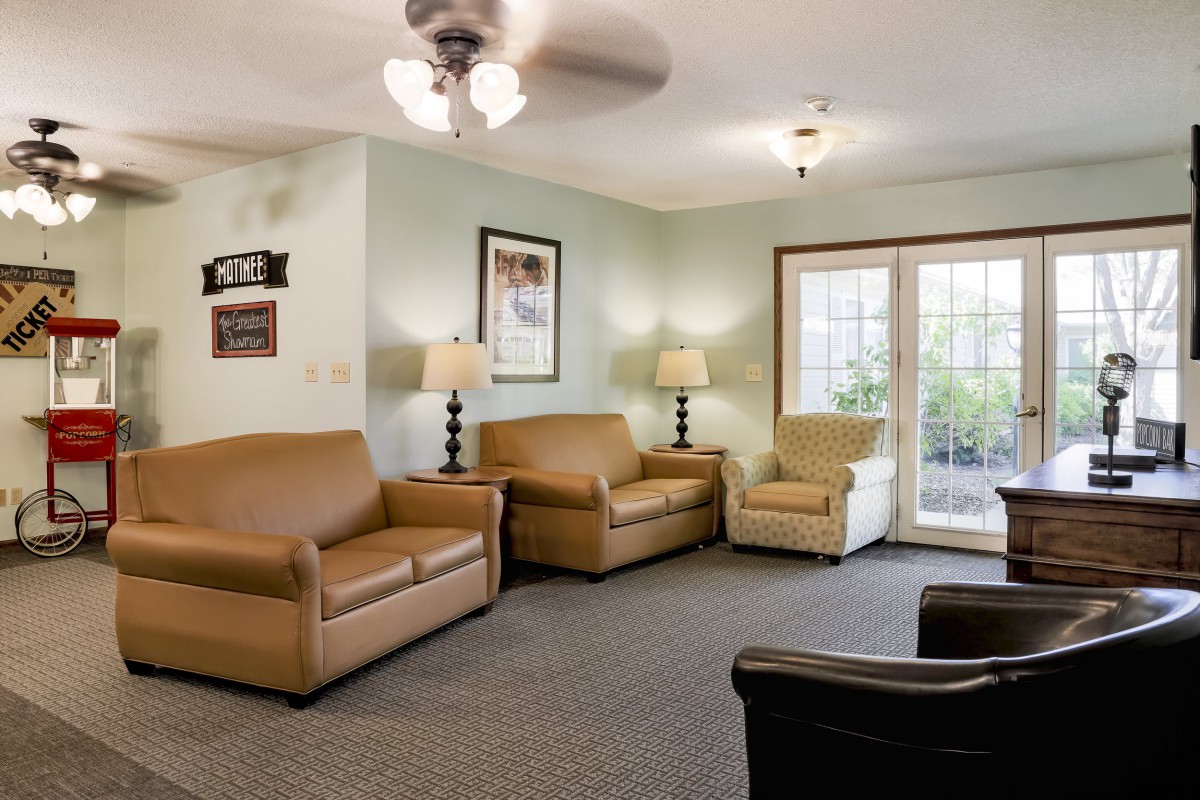 A cozy living room with sofas, armchairs, lamps, and a ceiling fan.