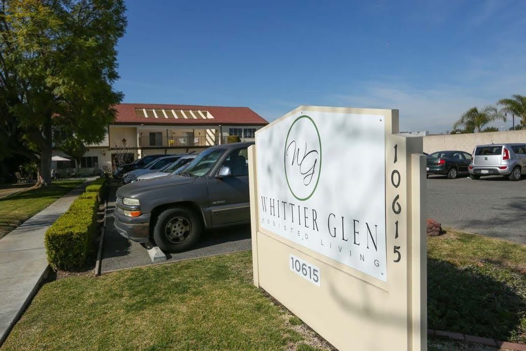 Entrance sign for Center Glen with a building and parked car in the background.