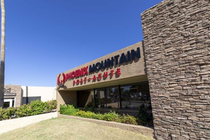 Exterior view of a restaurant with stone facade and signage on a sunny day.