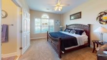A cozy bedroom featuring a large bed, ceiling fan, and bright window.