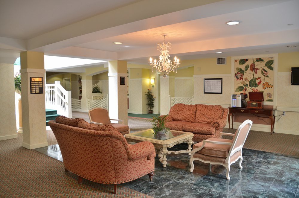 A cozy hotel lobby with comfortable seating, a chandelier, and a glass coffee table.
