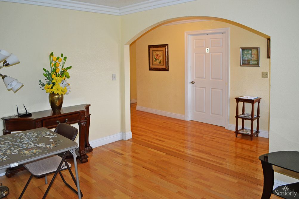 A well-lit living room with hardwood floors and elegant decor, featuring an archway leading to another area.