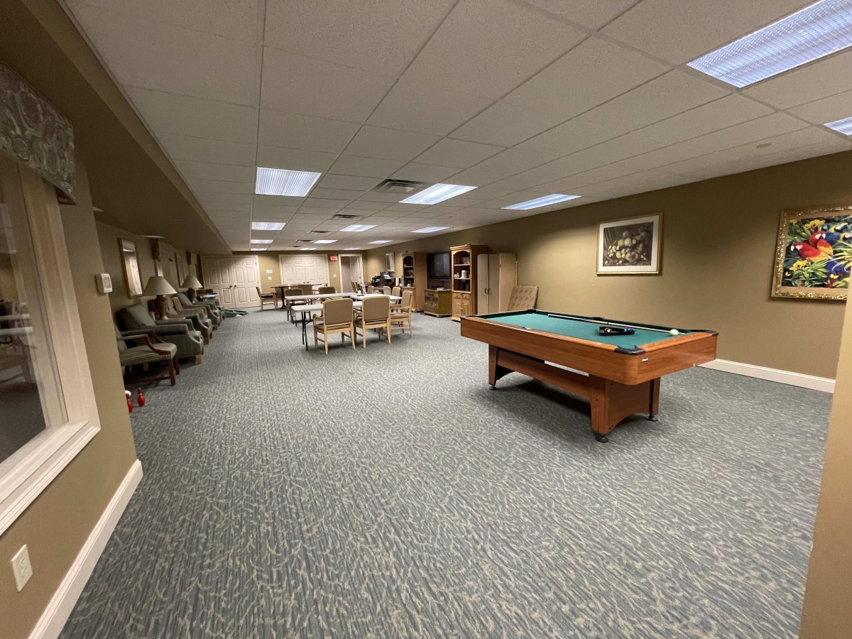 A spacious game room featuring a pool table and various seating areas.